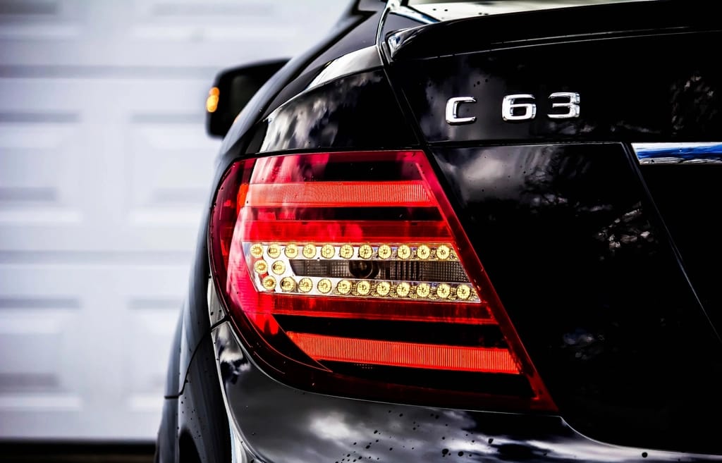 Glossy black car tail light reflecting studio lights